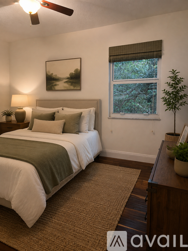 A bedroom with a bed, a plant, and a window.