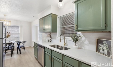 A kitchen with green cabinets and a white countertop.