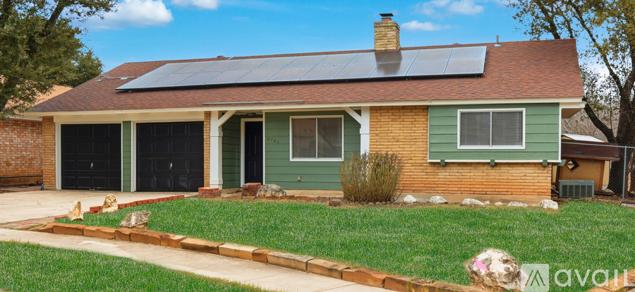 A house with a green front yard and solar panels on the roof.