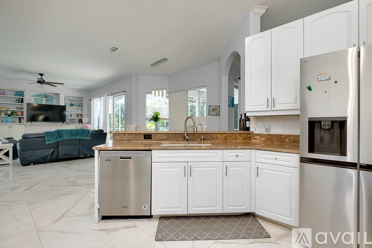 A kitchen with white cabinets and a stainless steel refrigerator.