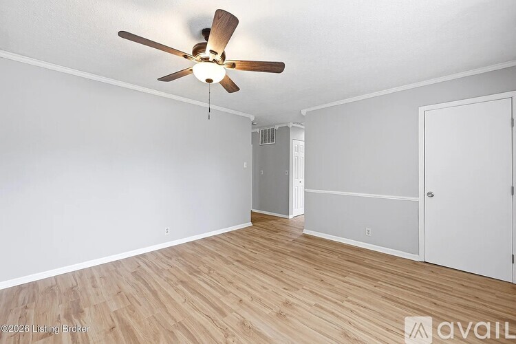 A room with a ceiling fan and wooden flooring.