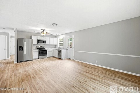 A kitchen with wooden floors and white cabinets.