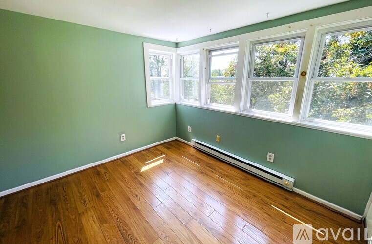 A room with green walls and wood flooring with a window.
