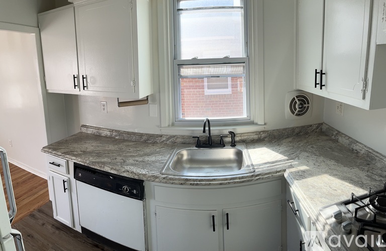 A kitchen with a marble countertop and white cabinets.