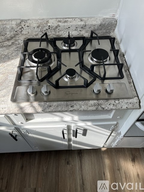 A black and silver gas stove with four burners is installed in a kitchen with a granite countertop.