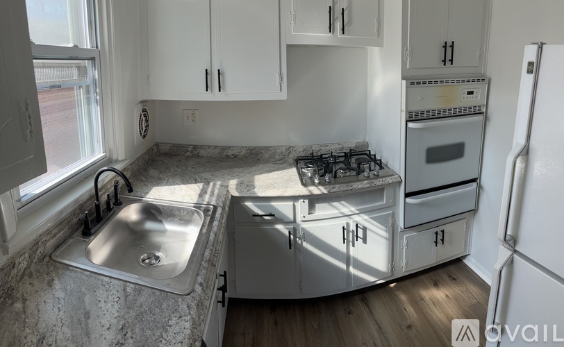 A kitchen with a stove, sink, and cabinets.
