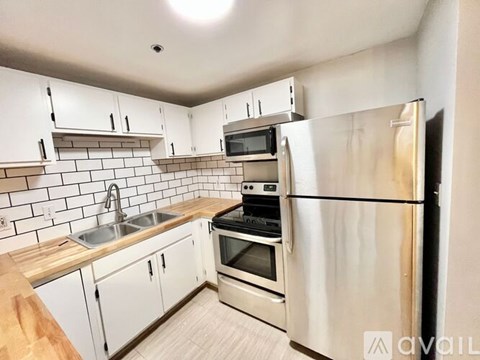 A kitchen with white cabinets and a stainless steel refrigerator.