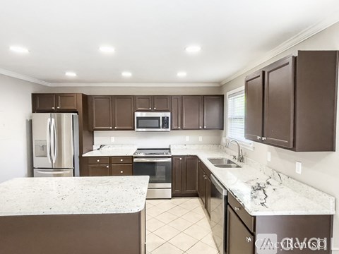 A kitchen with brown cabinets and a marble countertop.