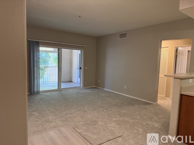 A spacious living room with a carpeted floor and sliding glass doors leading to a balcony.