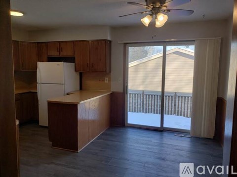 A kitchen with a refrigerator, cabinets, and a ceiling fan.