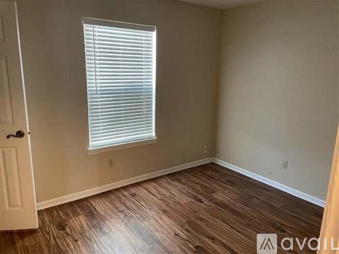 A room with wooden flooring and a window with blinds.