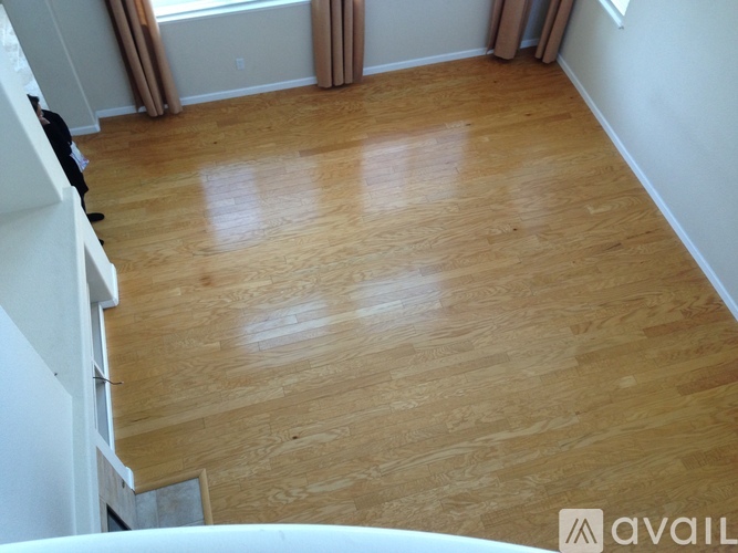 A room with wooden flooring and a window with curtains.