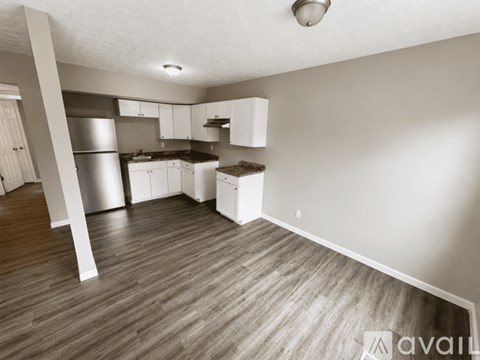 A kitchen with white cabinets and a wooden floor.