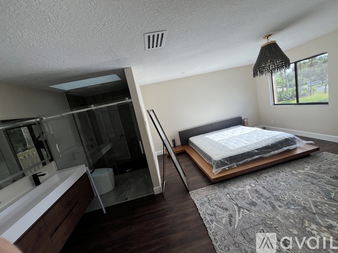 A bedroom with a bed, a bathtub, and a window.