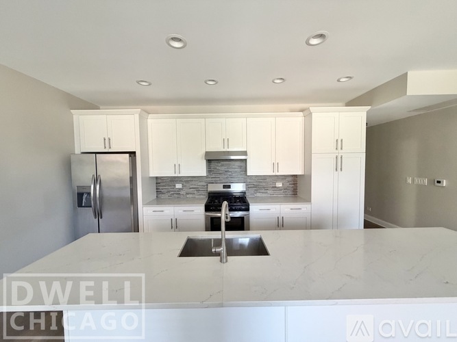 A kitchen with white cabinets and a marble countertop.