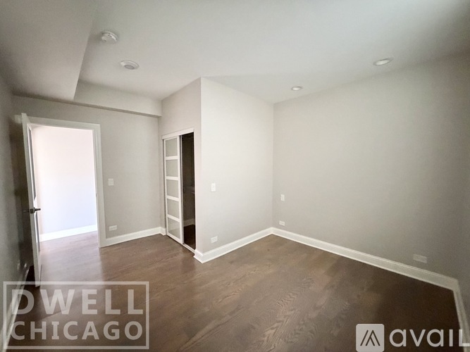 A spacious room with wood flooring and white walls.