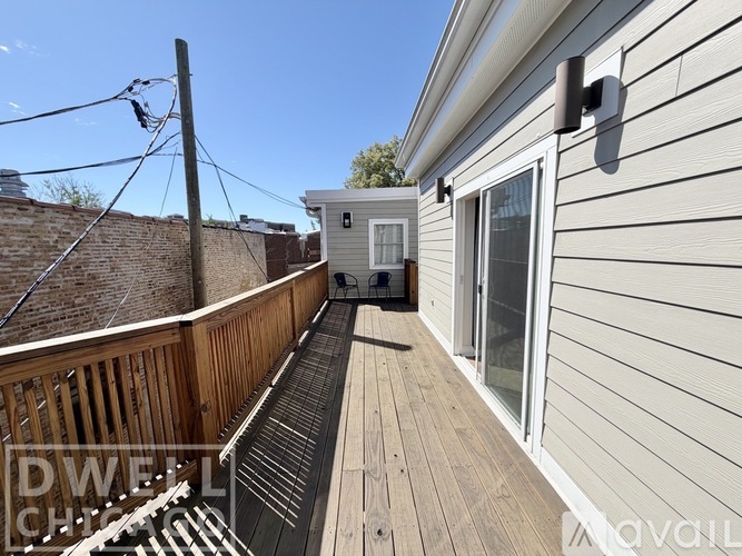 A deck with a wooden railing and a small building in the background.