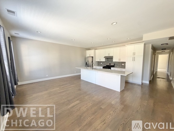 A spacious kitchen with white cabinets and a wooden floor.