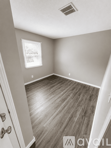 A room with wooden flooring and a door leading to another room.