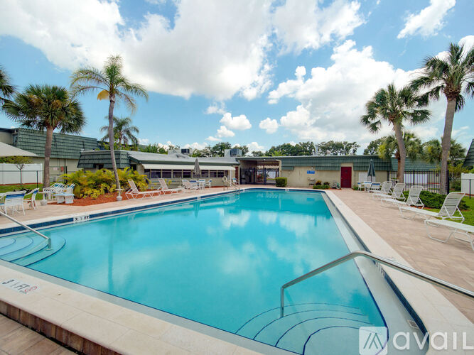 A large outdoor swimming pool surrounded by palm trees and lounge chairs.