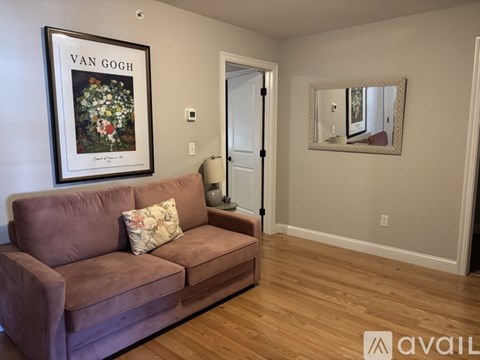 A living room with a brown couch and a Van Gogh painting on the wall.