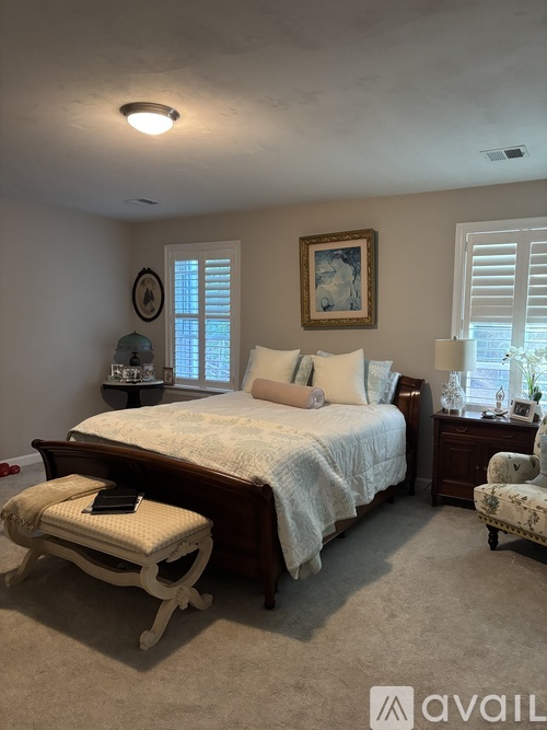 A bedroom with a bed, chair, and window.