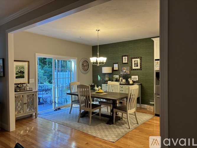 A dining room with a table set for four and a chandelier hanging from the ceiling.