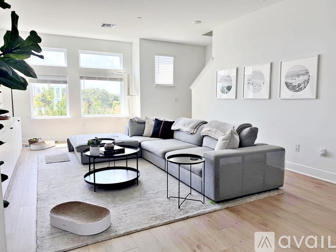 A living room with a grey sofa, a black coffee table, and three framed pictures on the wall.