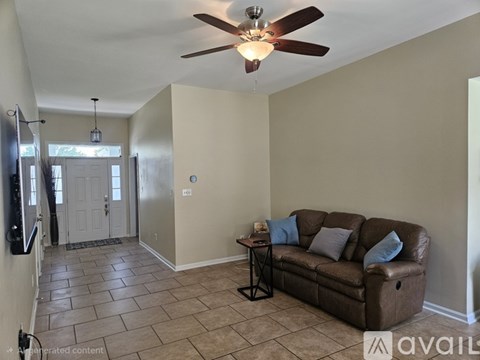 A living room with a brown couch and a ceiling fan.
