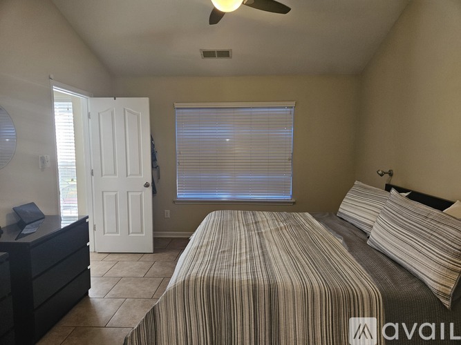 A bedroom with a bed, dresser, and window with blinds.