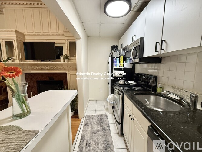 A kitchen with white cabinets and black countertops.