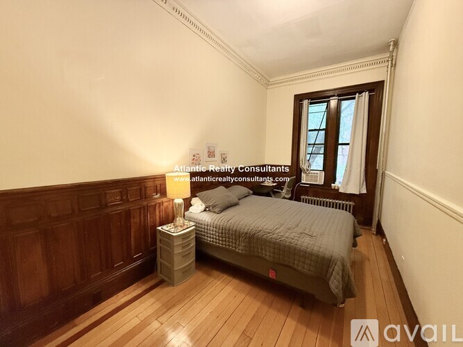 A bedroom with a bed, nightstand, and window.