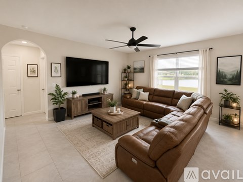 A living room with a brown leather sofa and a flat screen TV mounted on the wall.