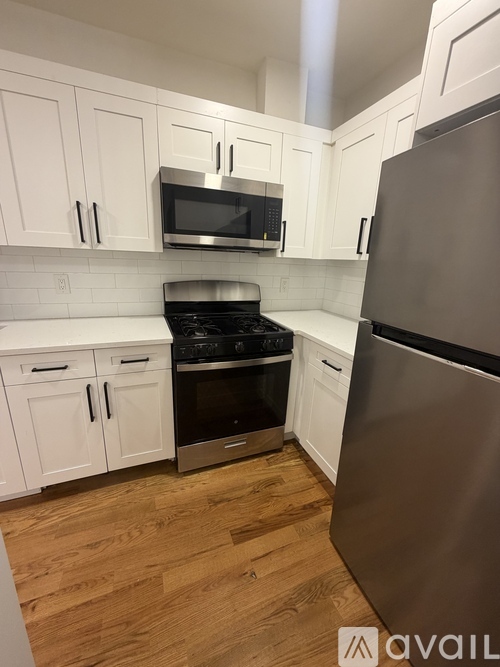 A kitchen with white cabinets and a stainless steel refrigerator.