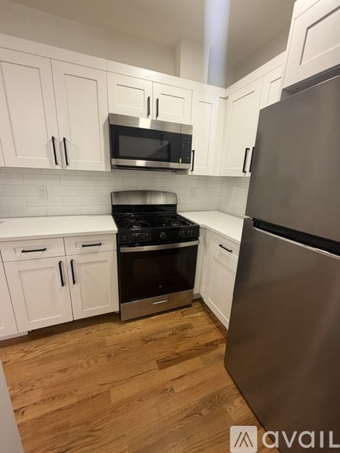 A kitchen with white cabinets and a stainless steel refrigerator.