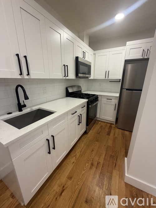 A kitchen with white cabinets and a wooden floor.