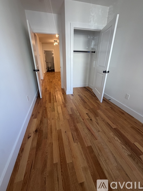 A hallway with wooden floors and white walls.