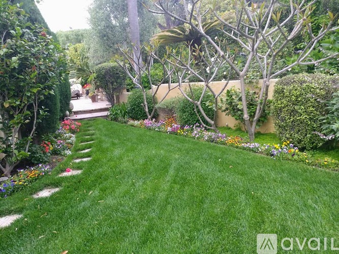 A well-maintained garden with a lawn, trees, and flowers.
