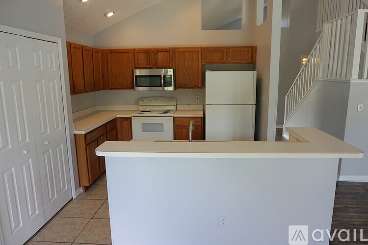 A kitchen with a white counter top and wooden cabinets.