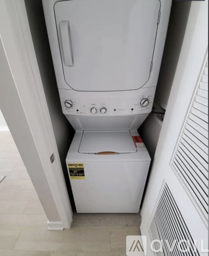 A white dryer is sitting in a small space between a wall and a radiator.