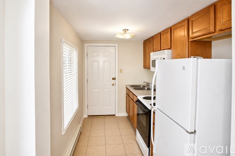 A kitchen with white appliances and wooden cabinets.