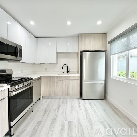 A modern kitchen with white cabinets and stainless steel appliances.
