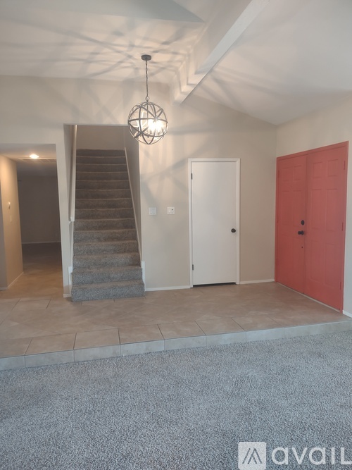 A room with a staircase and a red door.