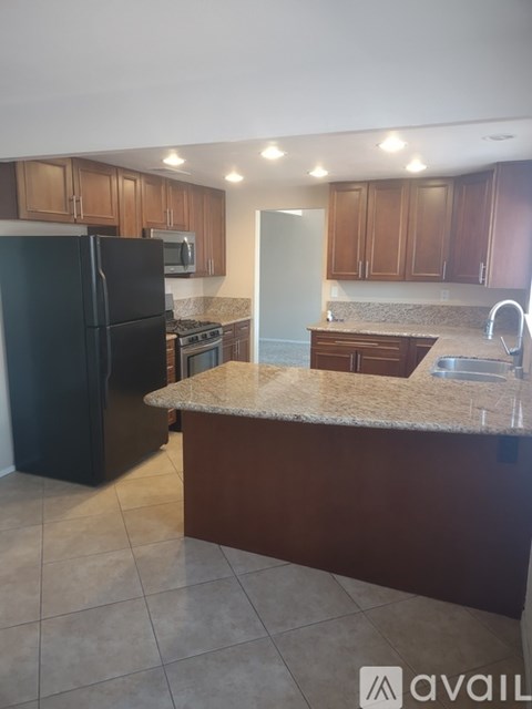 A kitchen with brown cabinets and a black refrigerator.