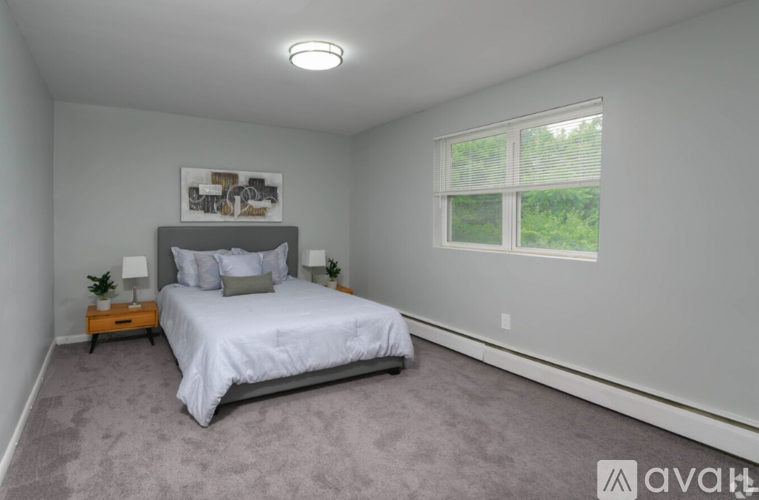 A bedroom with a bed, nightstand, and window.