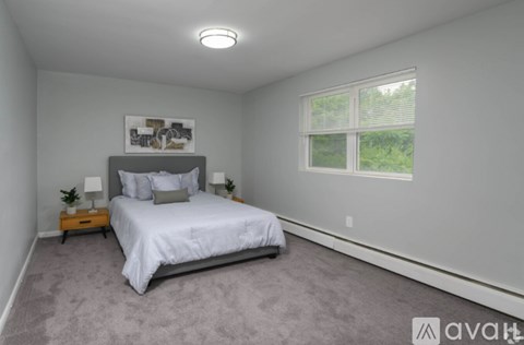 A bedroom with a bed, nightstand, and window.