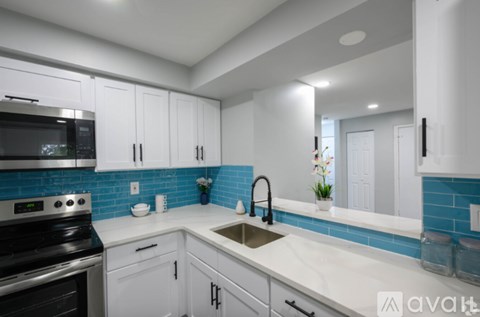 A kitchen with white cabinets and a black microwave.