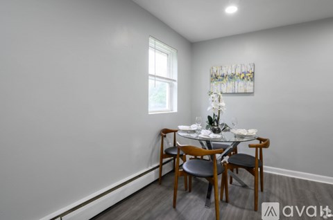 A dining room with a table set for two and a painting on the wall.