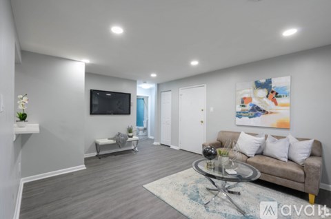 A living room with a couch, a television, and a painting on the wall.