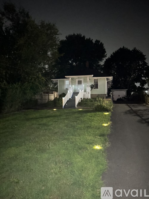 A house is lit up at night with lights on the lawn.